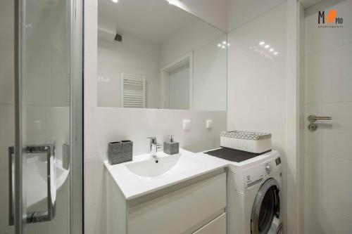 baño blanco con lavadora y lavamanos en MS Pro Apartamenty De Lux Class, en Kołobrzeg