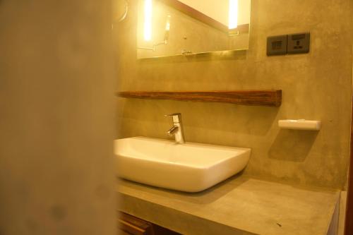 Red Coconut Villa في بينتوتا: حمام مع حوض أبيض ومرآة