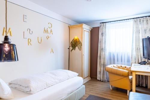 a bedroom with a bed and a desk and a window at Romantikhotel Rebstock art & design in Kehl am Rhein