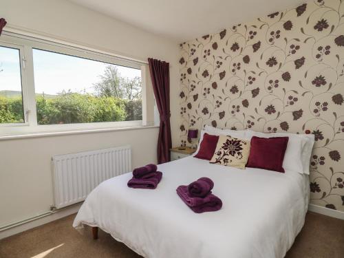 a bedroom with a bed with purple towels on it at 24 Dolithel in Tywyn