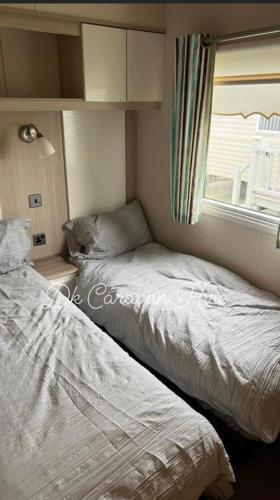 2 camas en una habitación pequeña con ventana en Luxury Caravan in Towyn North Wales, en Abergele