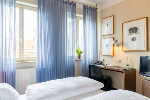 a hotel room with a bed and a desk and a window at Romantikhotel Rebstock art & design in Kehl am Rhein
