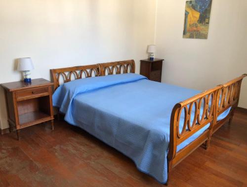 a bedroom with a wooden bed with blue sheets and two tables at Il lupo e la volpe - parcheggio gratis in Centobuchi