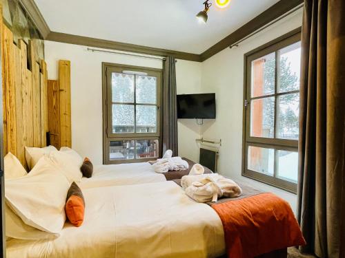 deux lits dans une chambre avec deux fenêtres dans l'établissement ARC 1950 Appt 6/8 pers LUXE MANOIR SAVOIE - SKI IN SKI OUT, à Arc 1950