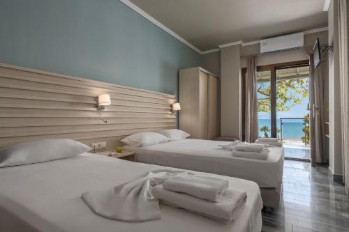 two beds in a room with a view of the ocean at Alkioni By The Sea in Siviri