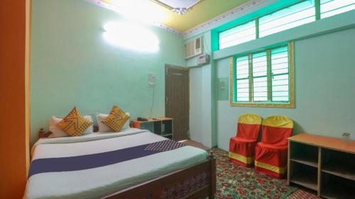 a bedroom with a bed and two chairs and a desk at New Happy palace Inn Gaya Near By Mahabodhi Temple in Gaya