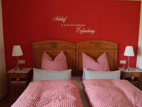Ferienwohnung Wohnsiedler في Rot am See: غرفة نوم بسريرين وجدار احمر