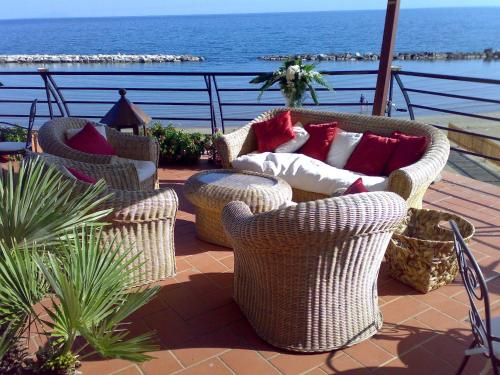 three wicker chairs with pillows on a patio overlooking the ocean at Grand Hotel Fagiano Palace in Formia