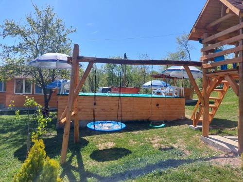 a swing in a yard with a pool at Stelele Coziei in Valcea