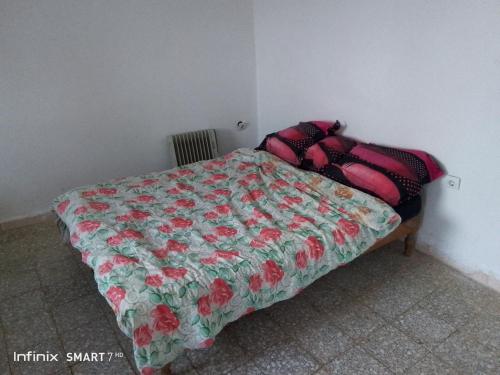 a bedroom with a bed with a floral comforter at Jerry's hole in Tipaza