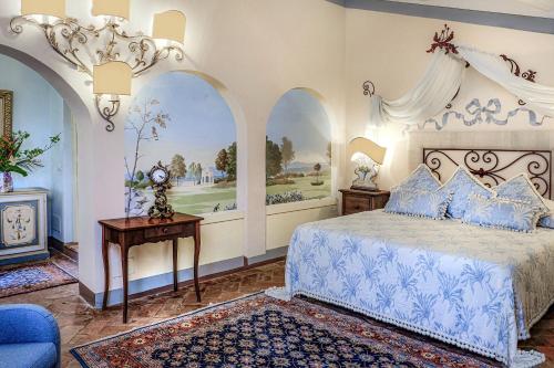 a bedroom with a blue and white bed and a table at Il Falconiere Relais & Spa in Cortona