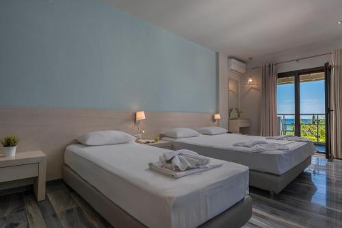 a hotel room with two beds and a balcony at Alkioni By The Sea in Siviri
