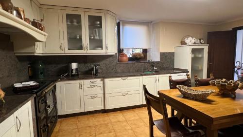 cocina con armarios blancos y mesa de madera en Casa Camino do Eume, en A Coruña