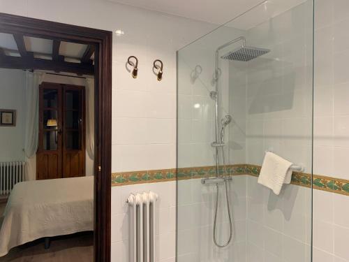 uma casa de banho com uma cabina de duche ao nível do chão ao lado de uma cama em El Jardín del Laurel em Candelario