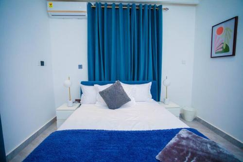 Un dormitorio con una cortina azul y una cama en The Pearl - Legacy - 1st floor, en Kumasi