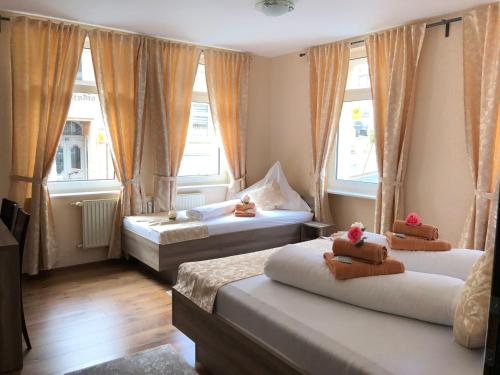 a bedroom with two beds and two windows at Pension Goldenes Vogtland in Adorf