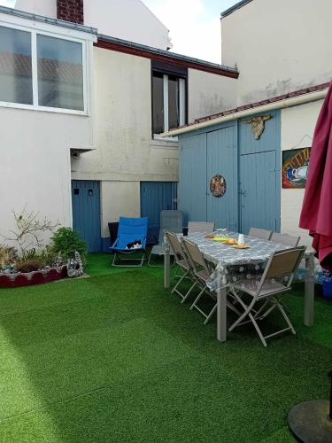 a patio with a table and chairs on grass at Petite maison indépendante in Le Havre