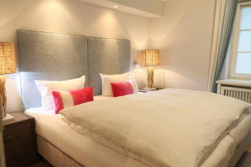 a bedroom with a large white bed with red pillows at Osterweg-53c-DHH in Wenningstedt
