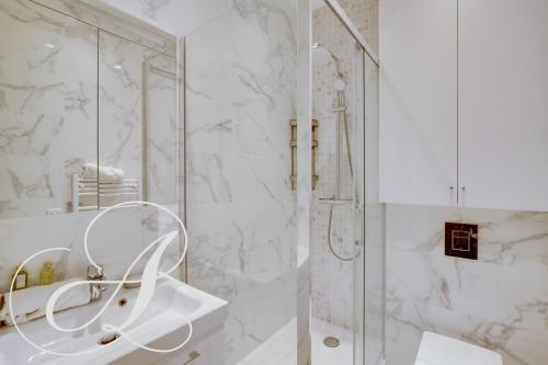 une salle de bain blanche avec une douche et un lavabo dans l'établissement Roxane, 2 chambres dont une en souplex Paris 14e, à Paris