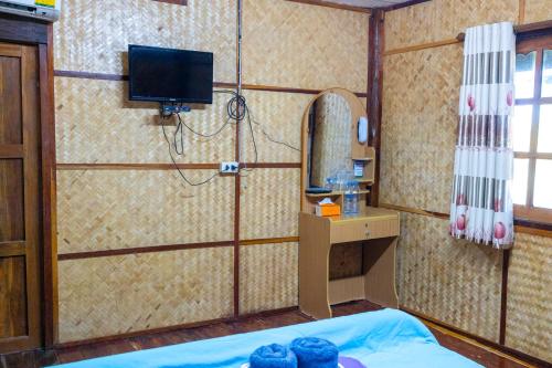 Zimmer mit einem Bett, einem Spiegel und einem TV. in der Unterkunft Ruenpakkiangnan เรือนพักเคียงน่าน in Phitsanulok