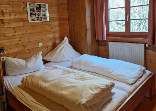 a bed in a wooden room with two pillows at Ferienhaus Neckar 34 in Hayingen