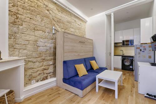 - un salon avec un canapé bleu et un mur en briques dans l'établissement Beau studio 2P en plein cœur du 2e, à Paris