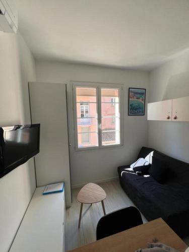- un salon avec un canapé noir et une fenêtre dans l'établissement Studio à Bandol en bord de mer, à Bandol