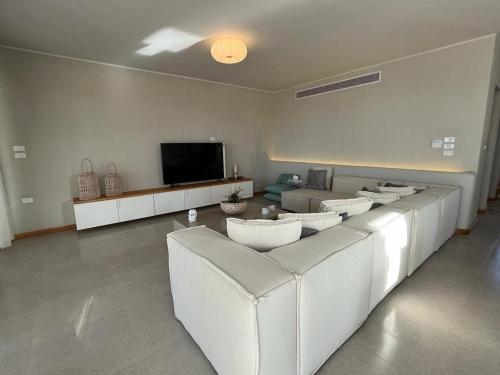 sala de estar con sofás blancos y TV de pantalla plana en Villa Almaza 5 bedrooms, en Marsa Matruh