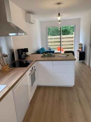 une cuisine avec des armoires blanches et un plancher en bois dans l'établissement Jolie Maison en pleine nature-proche du lac, à Parentis-en-Born