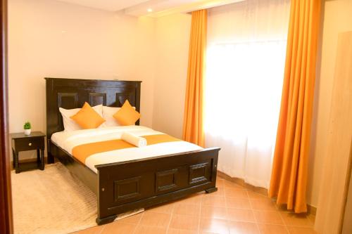 1 dormitorio con 1 cama con cortinas de color naranja y ventana en Effie Homes en Naivasha