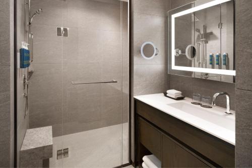 uma casa de banho com um chuveiro, um lavatório e um espelho. em بيت مطل ع الخمسين em Sanʼah