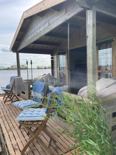 a deck with chairs and a house on the water at Luxury Experience in Off The Grid Lodge at an Amazing Lake Vinkeveense Plassen in Vinkeveen