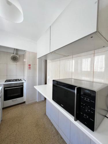 a white kitchen with a microwave and a stove at Relógio Guest House in Porto