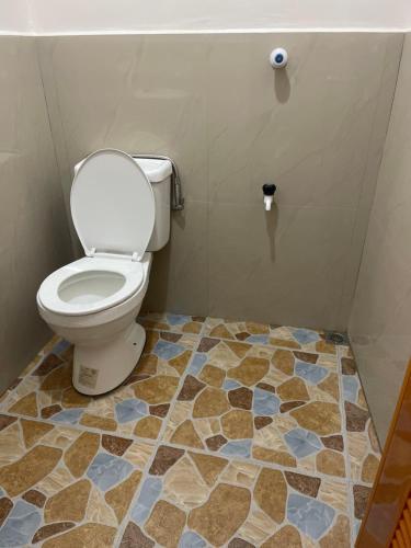 a bathroom with a toilet and a tiled floor at Maria kulafu studio 2 in Masbate
