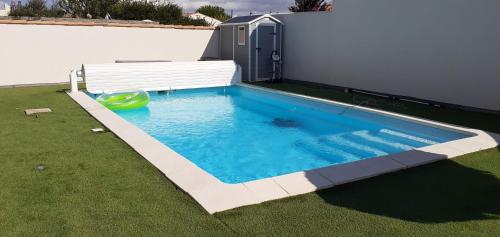 une piscine avec un espace vert devant un immeuble dans l'établissement Villa Louna, à Châtelaillon-Plage