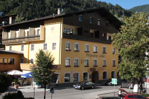 a large yellow building with cars parked in front of it at Hotel Schwarzer Adler Sillian in Sillian