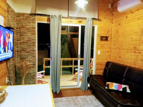 uma sala de estar com um sofá e uma porta de vidro deslizante em Hermosa cabaña con excelente vista panorámica em Piriápolis