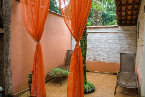 two orange curtains in a room with two chairs at Estalagem Wiesbaden in Monte Verde