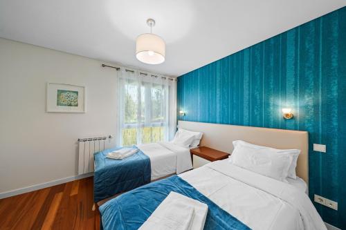 um quarto com 2 camas e uma parede azul em Bessa Luxury Flat by Amber Star Rent no Porto