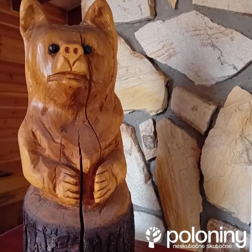 a carving of a bear sitting on a tree stump at Chata Exit in Kolonica
