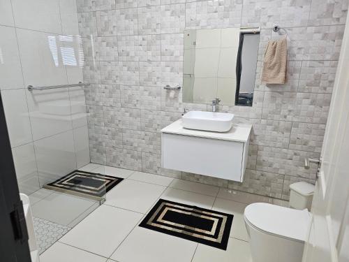 a white bathroom with a sink and a mirror at Li-Bru Self Catering Accommodation in Windhoek