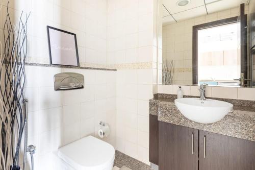 a bathroom with a sink and a toilet and a mirror at Frank Porter - BayCentral in Dubai