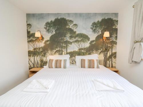 a bedroom with a white bed with a painting on the wall at Barcud Coch - Red Kite in Welshpool