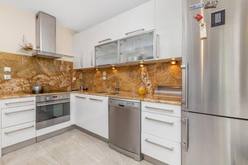 a kitchen with white cabinets and a stainless steel refrigerator at Seaside Apartment with Parking in Sopot by Renters in Sopot