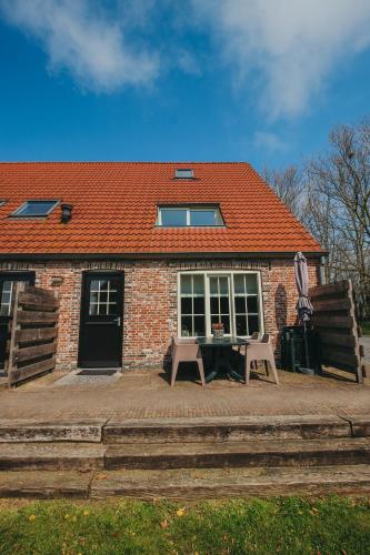a brick house with a table and chairs in front of it at Accommodatie in herbouwde boerenschuur Koestal in Retranchement