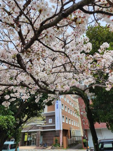 un arbre aux fleurs roses devant un bâtiment dans l'établissement Toyoko Inn Fujisan Numazu eki Kita guchi No 2, à Numazu