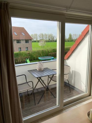 a balcony with a table and chairs and a window at 't Uilengat 6-8 persoons appartement in Retranchement