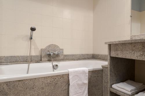 a bathroom with a bath tub with a towel at Château du Landel, The Originals Relais (Relais du Silence) in Bézancourt