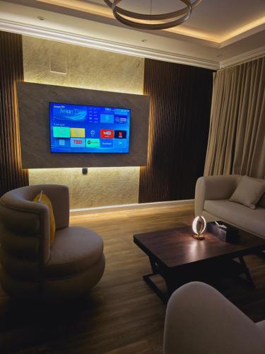 sala de estar con 2 sillas y TV en la pared en شقة مودرن غرفة وصالة في الملقا, en Riad