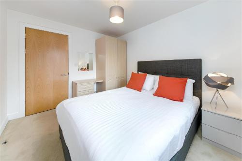 ロンドンにあるClerkenwell Serviced Apartmentsのベッドルーム(オレンジ色の枕が付いた大きな白いベッド付)